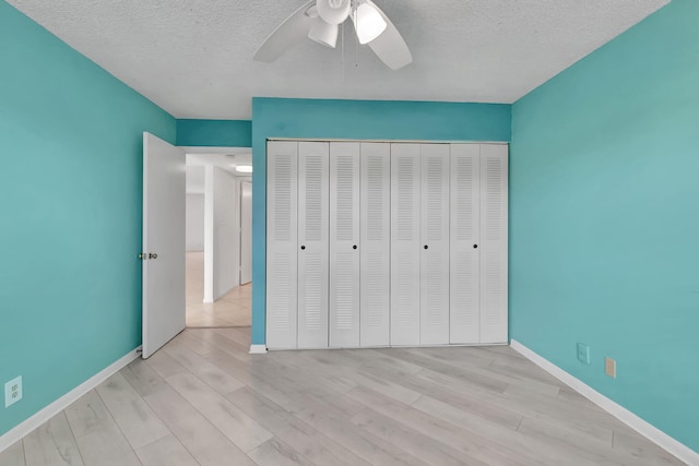 unfurnished bedroom with a textured ceiling, light hardwood / wood-style flooring, ceiling fan, and a closet