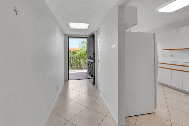 corridor with light tile patterned flooring and a textured ceiling