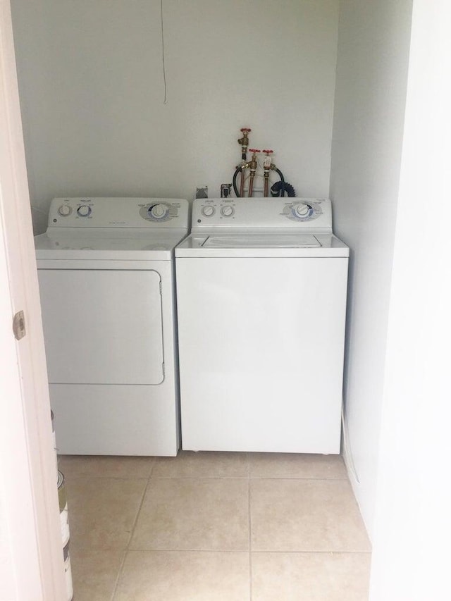 washroom with light tile patterned floors and washer and dryer