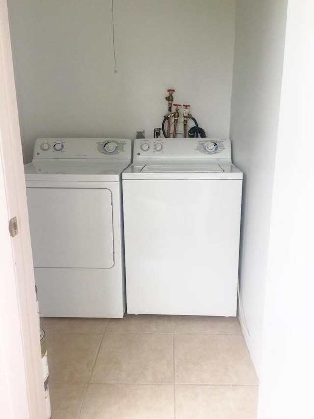 washroom featuring washer and clothes dryer, light tile patterned floors, and laundry area