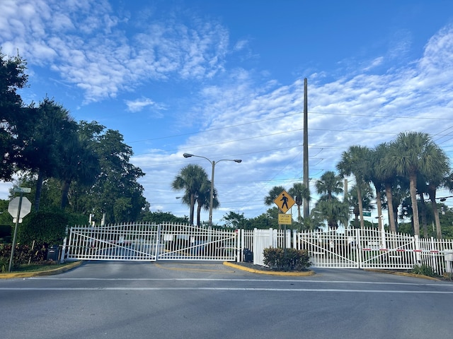 view of street featuring a gate, traffic signs, curbs, street lighting, and a gated entry