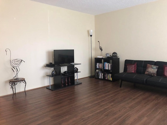 living area with baseboards, a textured ceiling, and wood finished floors