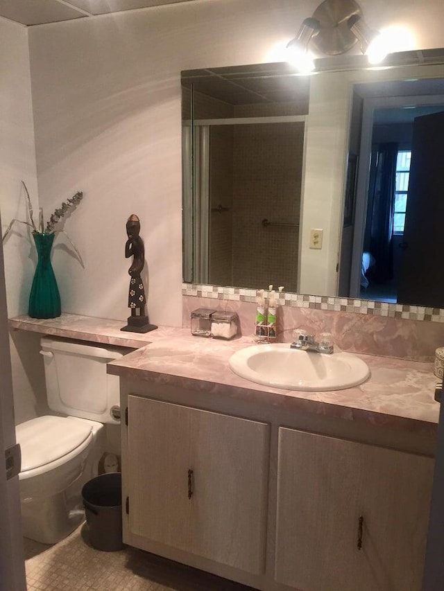 bathroom with vanity, toilet, an enclosed shower, and tasteful backsplash