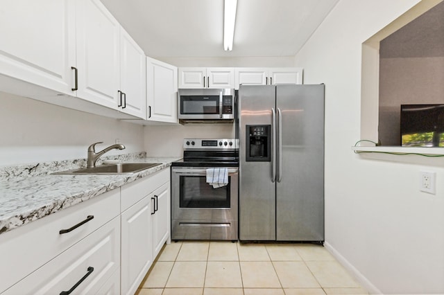 kitchen featuring light tile patterned flooring, white cabinetry, stainless steel appliances, and sink