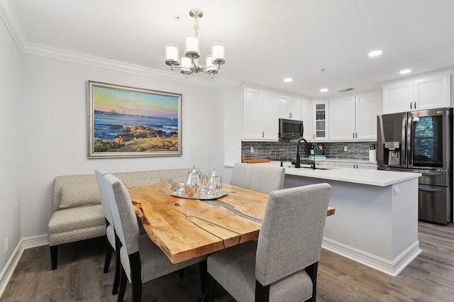 dining room featuring dark hardwood / wood-style floors, an inviting chandelier, crown molding, and sink