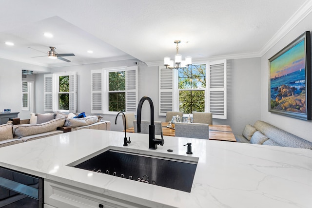 kitchen with ceiling fan with notable chandelier, sink, wine cooler, ornamental molding, and decorative light fixtures