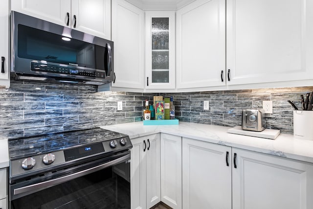 kitchen with decorative backsplash, electric range, white cabinetry, and light stone counters