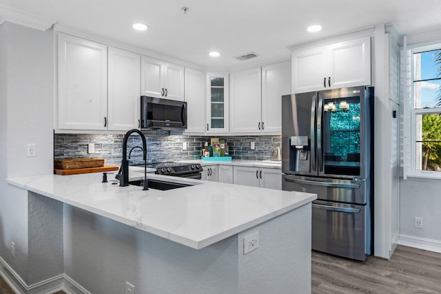 kitchen featuring kitchen peninsula, stainless steel refrigerator with ice dispenser, white cabinetry, and sink