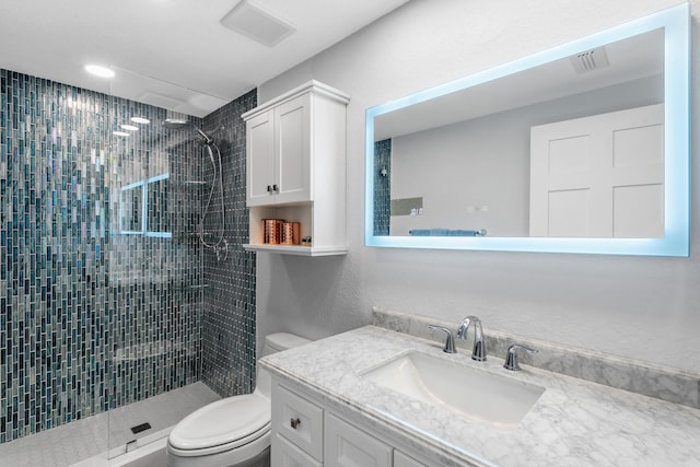 bathroom featuring vanity, toilet, and tiled shower