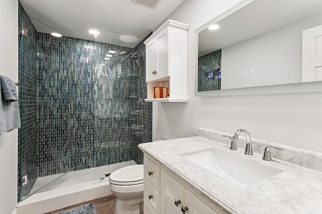 bathroom with a shower with door, vanity, wood-type flooring, and toilet