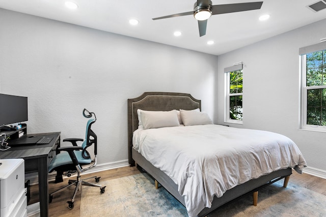 bedroom with hardwood / wood-style floors, ceiling fan, and multiple windows