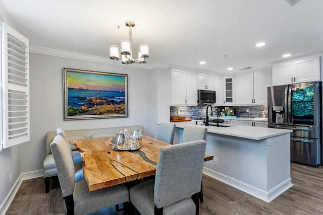 dining area featuring sink, dark hardwood / wood-style flooring, crown molding, and an inviting chandelier