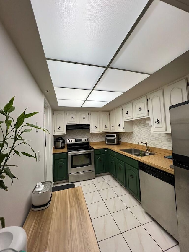 kitchen with green cabinetry, light tile patterned floors, appliances with stainless steel finishes, sink, and decorative backsplash