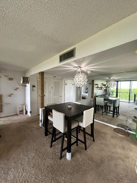 carpeted dining space featuring a textured ceiling and an inviting chandelier