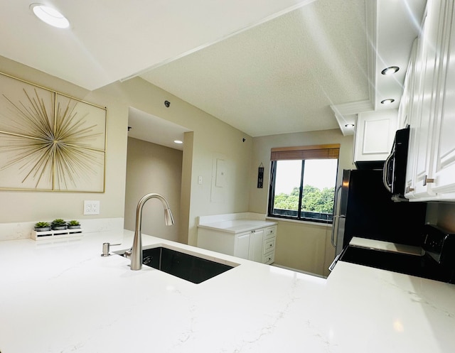 kitchen featuring white cabinetry, light stone counters, sink, and stainless steel range oven