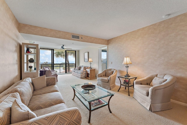 living room featuring a textured ceiling, ceiling fan, and light colored carpet