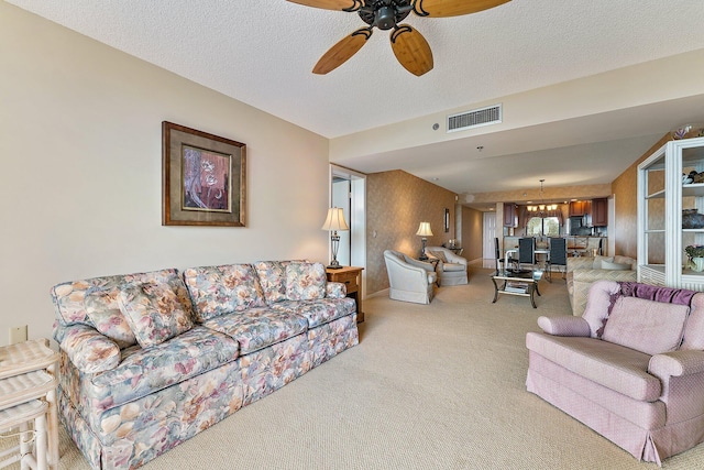 living room with ceiling fan with notable chandelier, light carpet, and a textured ceiling