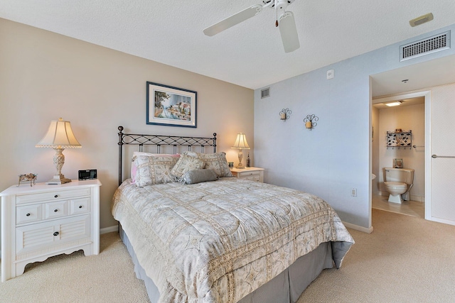 carpeted bedroom featuring ceiling fan, a textured ceiling, and ensuite bath