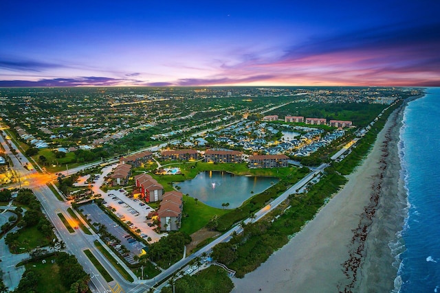 aerial view at dusk with a water view and a view of the beach