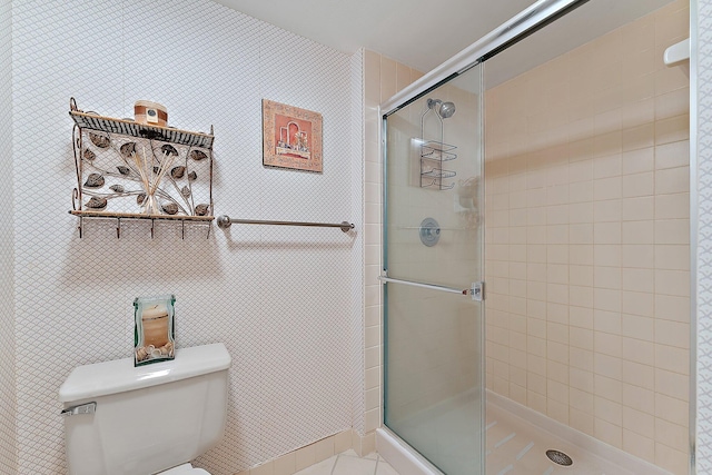 bathroom with a shower with door, toilet, and tile patterned flooring