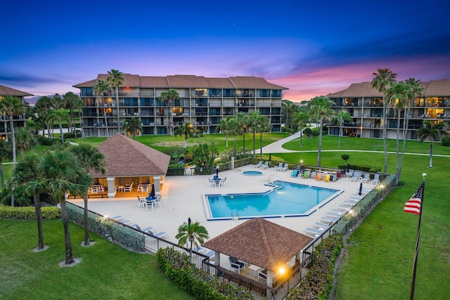 pool at dusk featuring a yard and a patio area