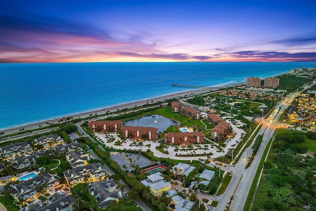 aerial view at dusk with a view of the beach and a water view