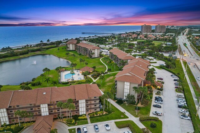 aerial view at dusk featuring a water view