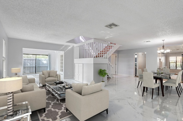 living room with a chandelier, a textured ceiling, and a wealth of natural light