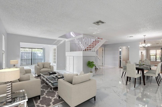 living room featuring a textured ceiling, plenty of natural light, and a notable chandelier