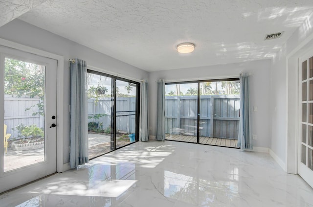 unfurnished room with a healthy amount of sunlight and a textured ceiling