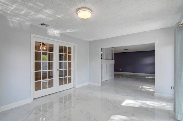 spare room with a textured ceiling and french doors