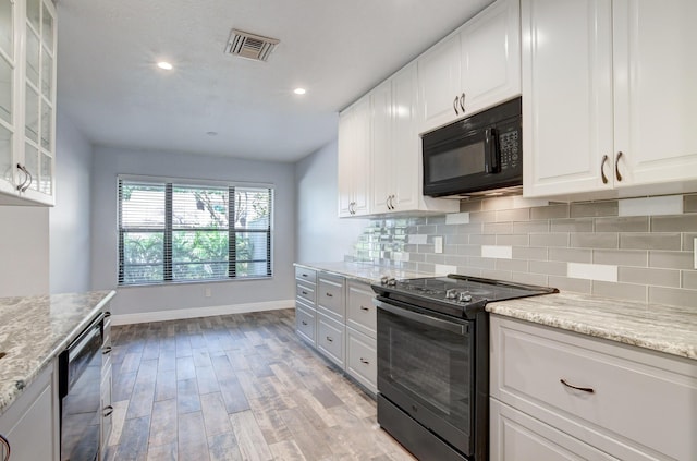 kitchen featuring light stone countertops, backsplash, black appliances, white cabinets, and light hardwood / wood-style floors