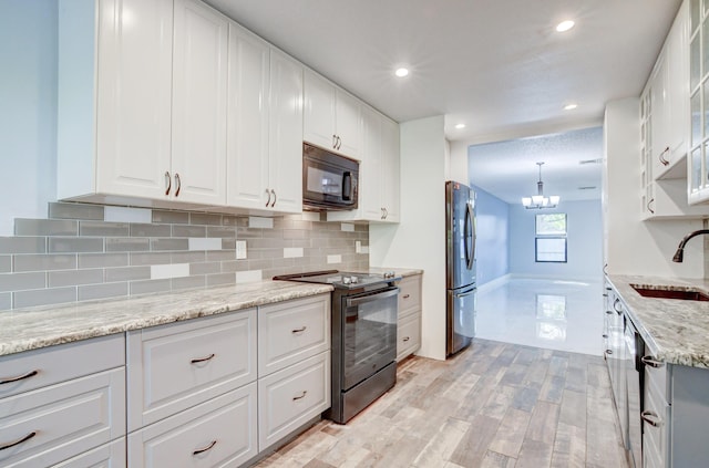 kitchen with white cabinets, sink, decorative light fixtures, light stone counters, and stainless steel appliances