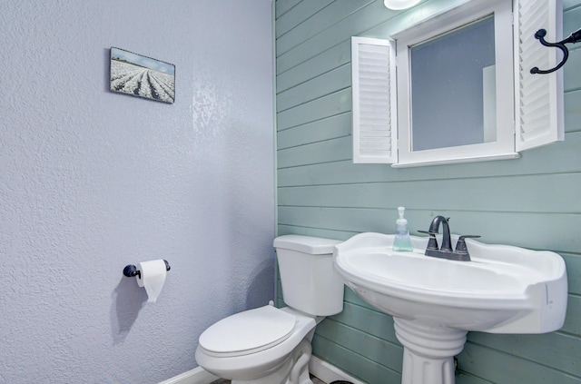 bathroom featuring wooden walls and toilet