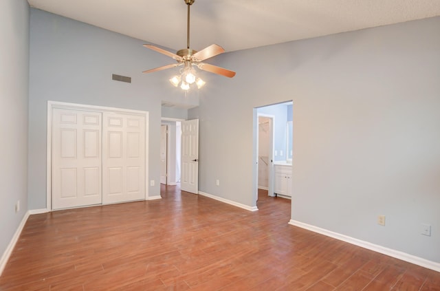 unfurnished bedroom with ensuite bath, ceiling fan, a closet, and wood-type flooring