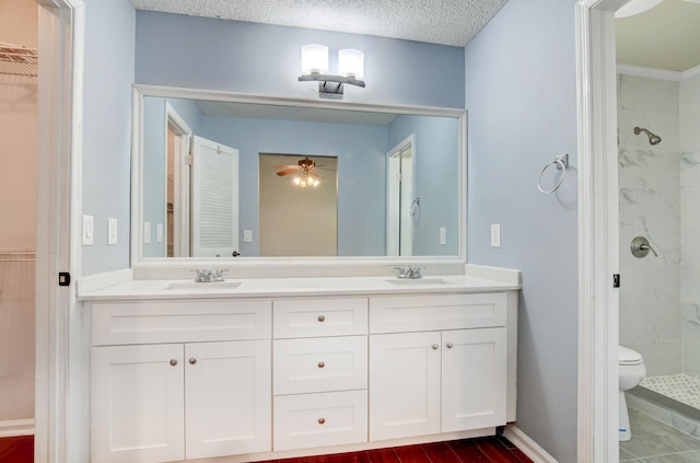 bathroom with a textured ceiling, ceiling fan, tiled shower, and vanity