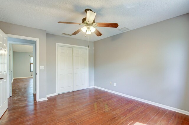 unfurnished bedroom with a textured ceiling, a closet, ceiling fan, and hardwood / wood-style flooring