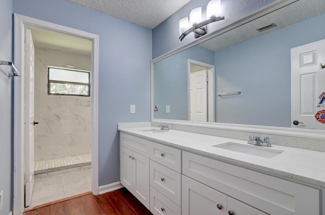 bathroom featuring tiled shower, hardwood / wood-style floors, a textured ceiling, and vanity