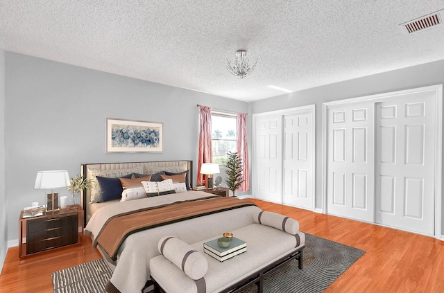 bedroom featuring multiple closets, a textured ceiling, and hardwood / wood-style flooring