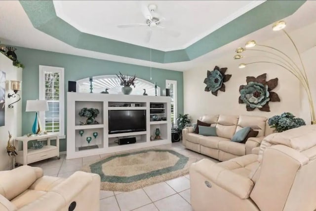 living room with a ceiling fan, a raised ceiling, and light tile patterned floors