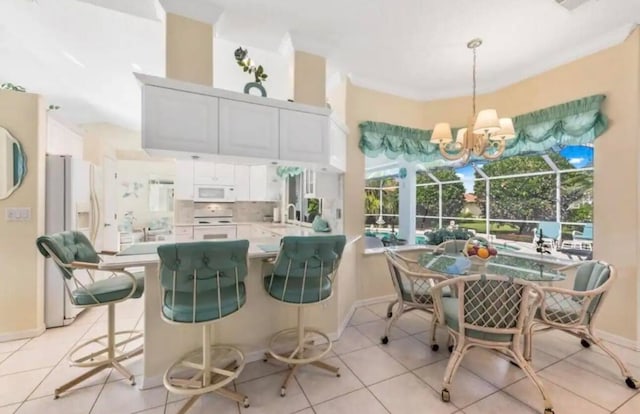 kitchen featuring light countertops, hanging light fixtures, white cabinetry, white appliances, and a peninsula