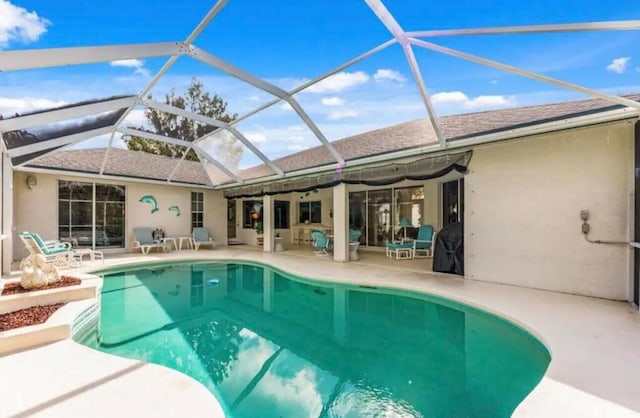 view of swimming pool with glass enclosure and a patio