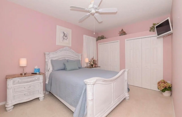 bedroom featuring multiple closets, light carpet, and a ceiling fan