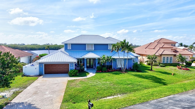 view of front of property featuring metal roof, a garage, decorative driveway, a front lawn, and a standing seam roof