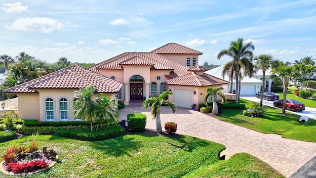 mediterranean / spanish-style house featuring a garage, a front yard, decorative driveway, and stucco siding