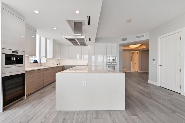 kitchen featuring white cabinetry, light hardwood / wood-style flooring, a spacious island, and a wall of windows