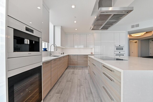 kitchen featuring a center island, light hardwood / wood-style floors, island exhaust hood, and white cabinetry