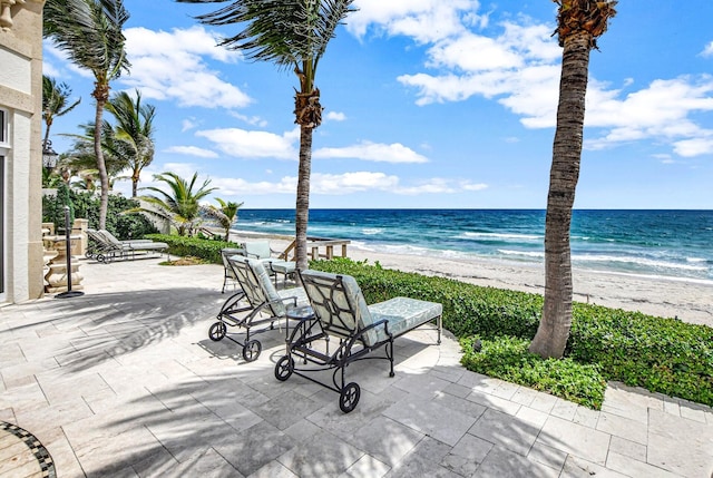 view of patio / terrace featuring a water view and a beach view