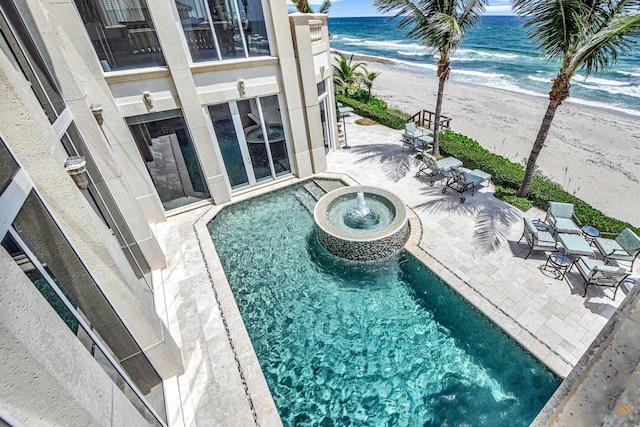 view of pool with a patio area, a water view, and a view of the beach