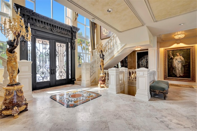 foyer with decorative columns, crown molding, a high ceiling, and french doors